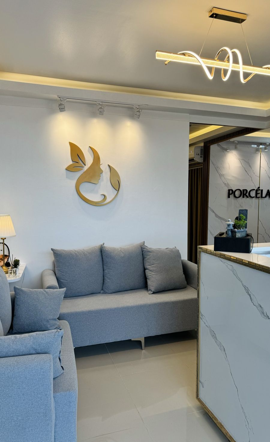 Porcélaine reception lounge with grey sofas, a gold logo on the wall and a marble reception counter